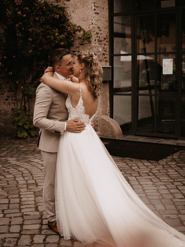 Das Bild zeigt ein glückliches, sich küssendes Brautpaar, welches das Hochzeitskleid bei uns in Wuppertal im Bridal Store erworben hat.