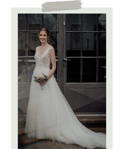Christina, eine glückliche Braut, welche ihr Hochzeitskleid bei uns im Wuppertaler Brautmodengeschäft erworben hat, posiert mit ihrem Brautstrauß auf diesem wunderschönen Foto.